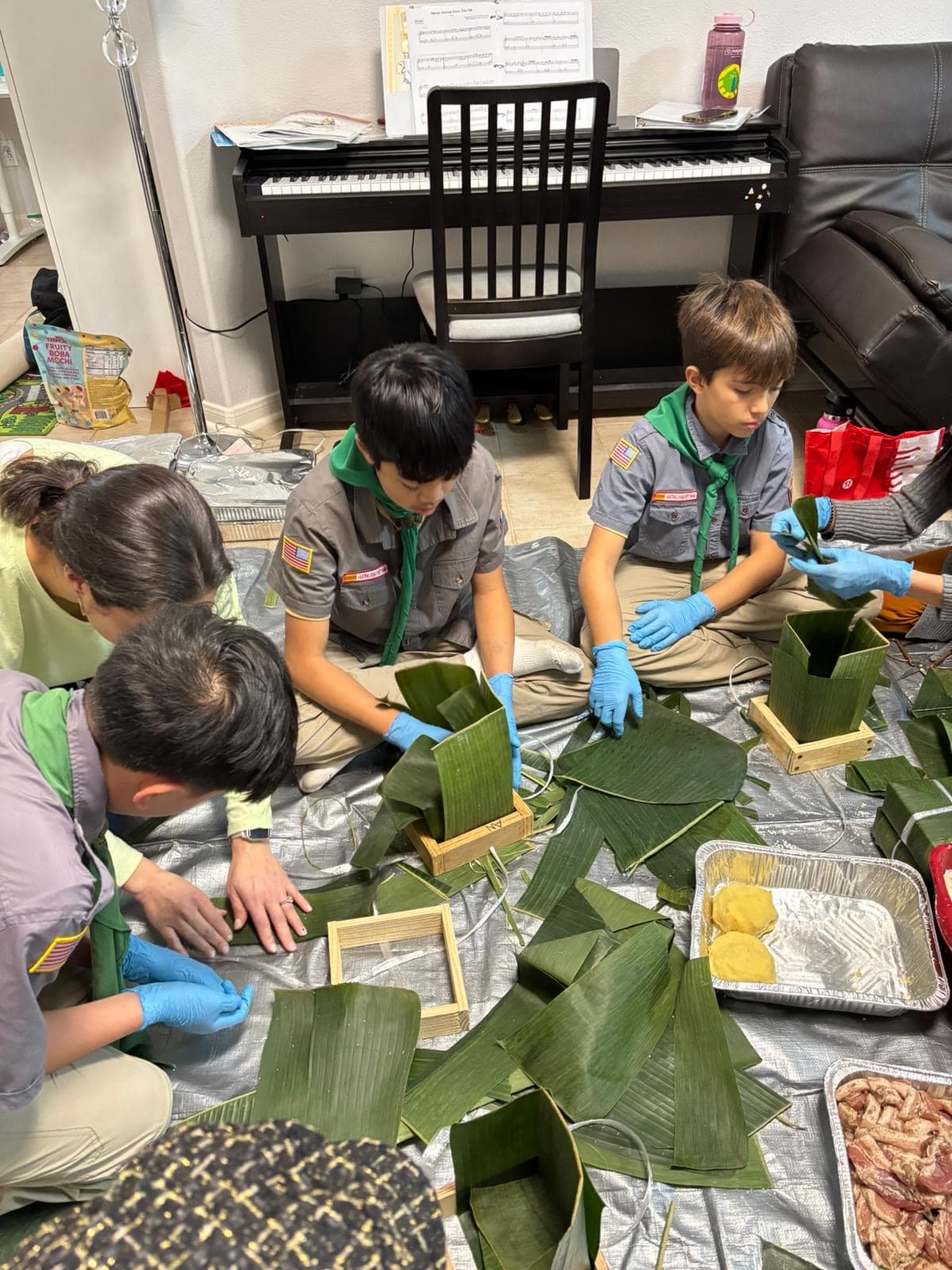 Scouts in uniform wrapping bánh chưng in banana leaves