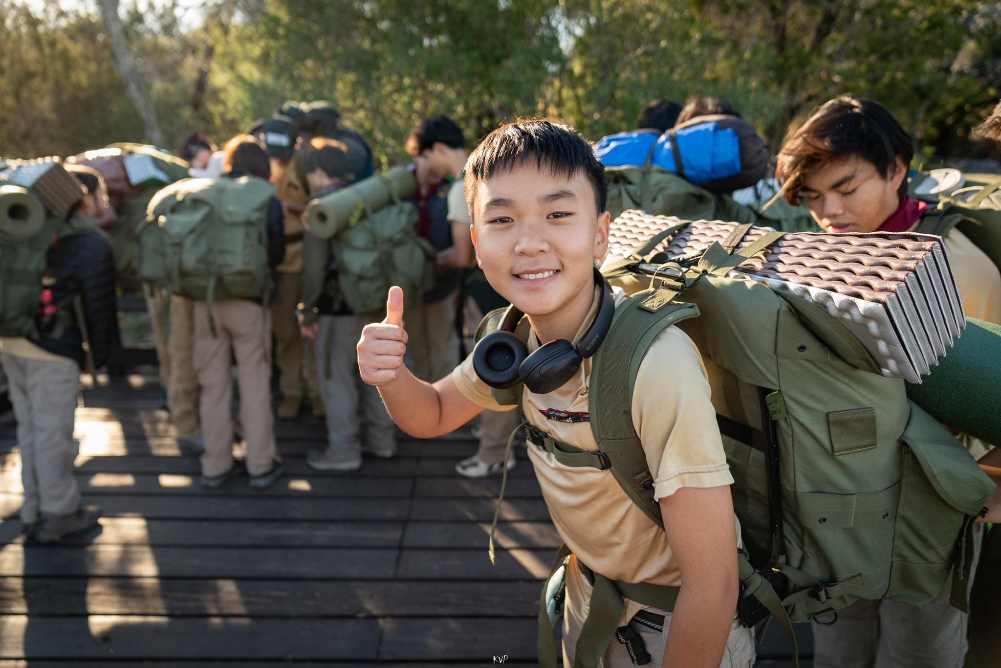 A young scout with a full pack gives a thumbs up